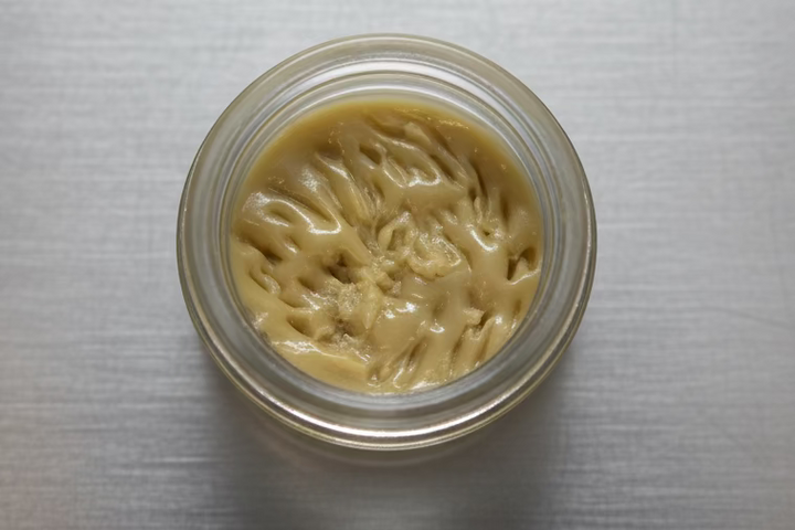 Cosmic Nectar Hash Rosin (H) 1G from I Am Hemp Inc, showing a close-up of the concentrate in a jar or container.